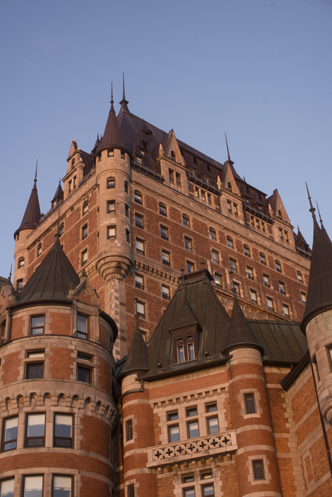 Detailed view of the turrets and brick facade of the Château Frontenac in Quebec City against a clear blue sky.
